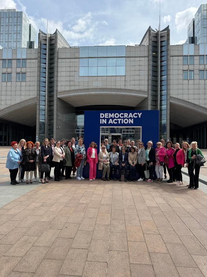 Gruppe vor Gebäude mit Banner „Democracy in Action“ posierend.
