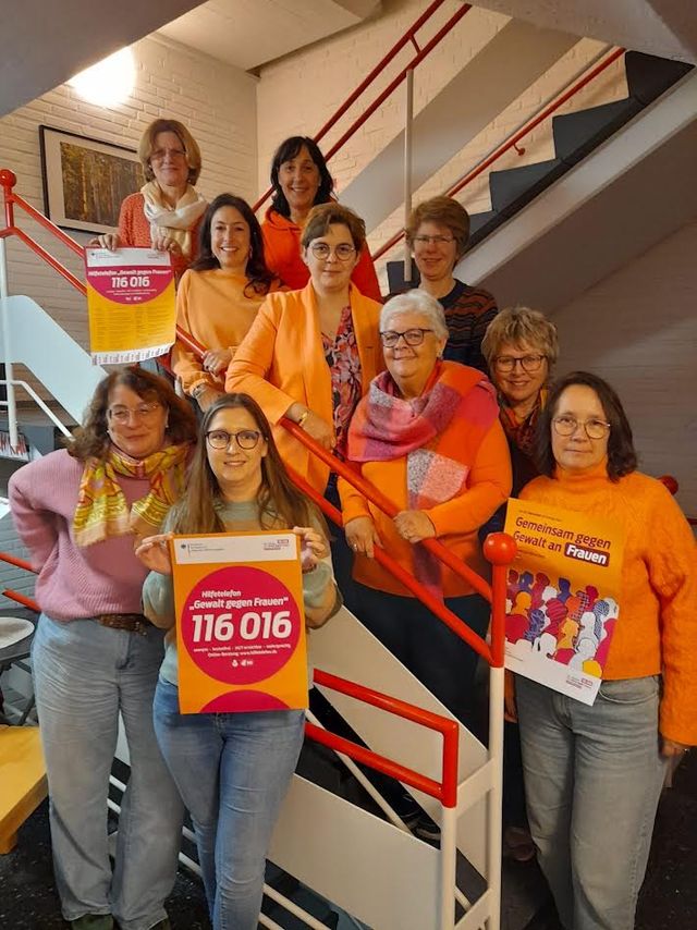 Gruppe von Frauen auf Treppe mit Aufklebern und Plakaten für Frauenrechte und Protestaktion.